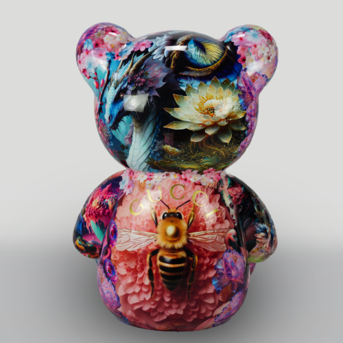 Colorful bear-shaped art piece with intricate designs including a dragon, flowers, a bee, and the word 